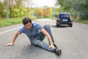 Hit and run concept: An injured man lying on the road in front of a car.